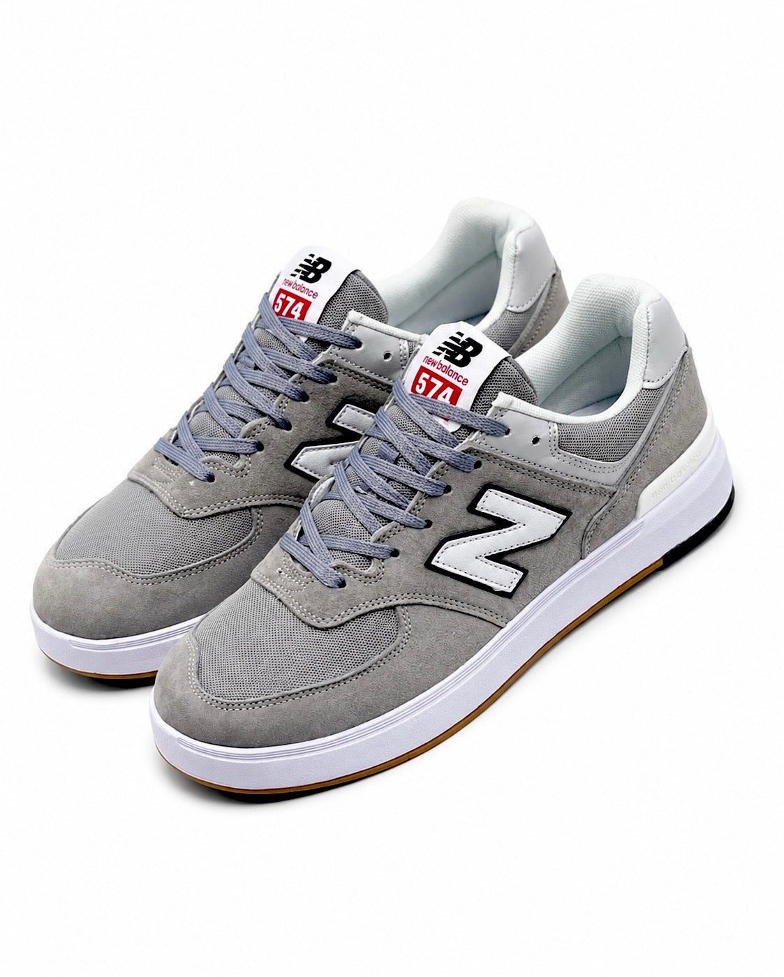 Cette chaussure est la New Balance Numeric 574 Vulc (référence couleur Grey/White), modèle classique iconique de la marque américaine New Balance