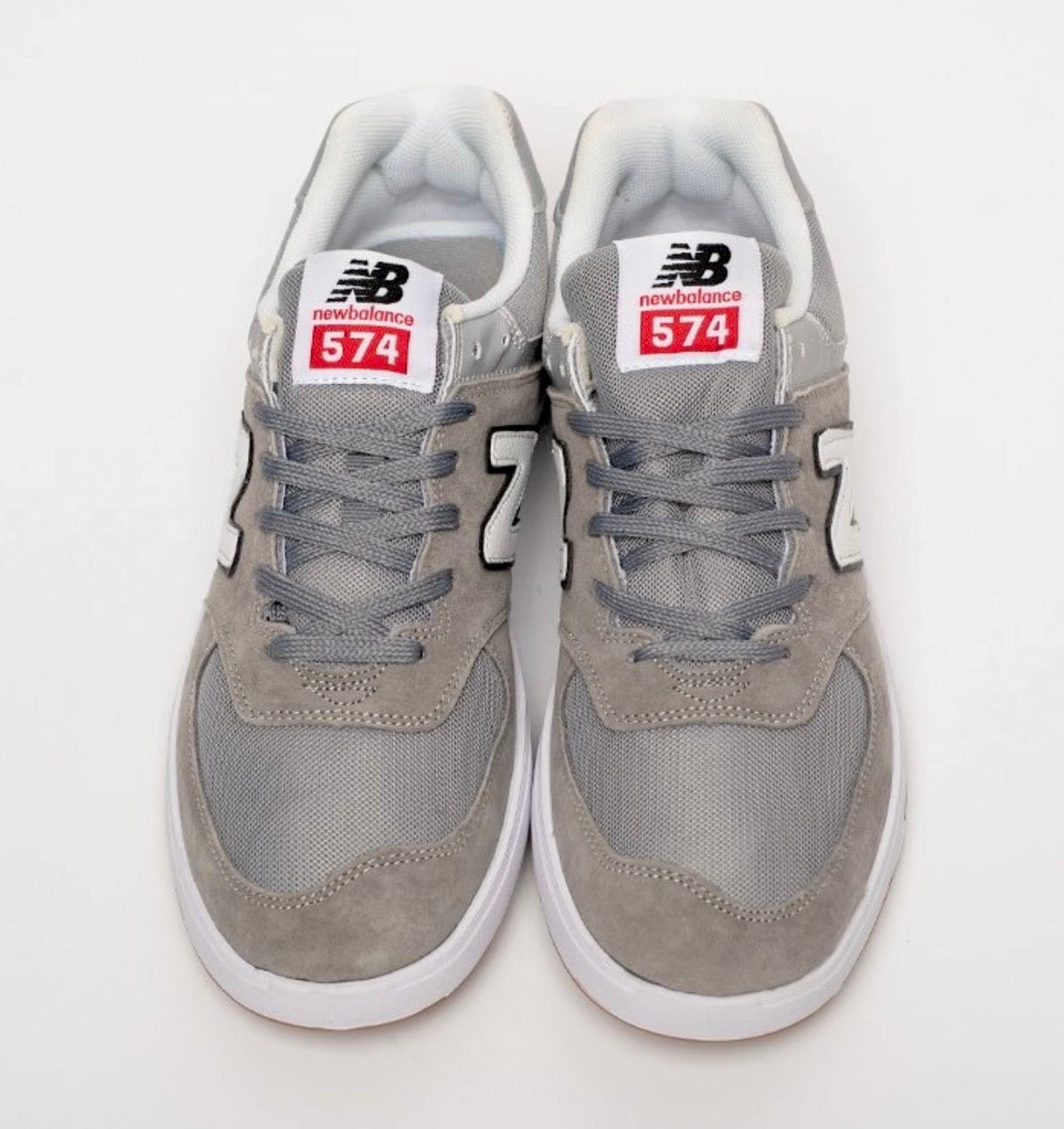 Cette chaussure est la New Balance Numeric 574 Vulc (référence couleur Grey/White), modèle classique iconique de la marque américaine New Balance