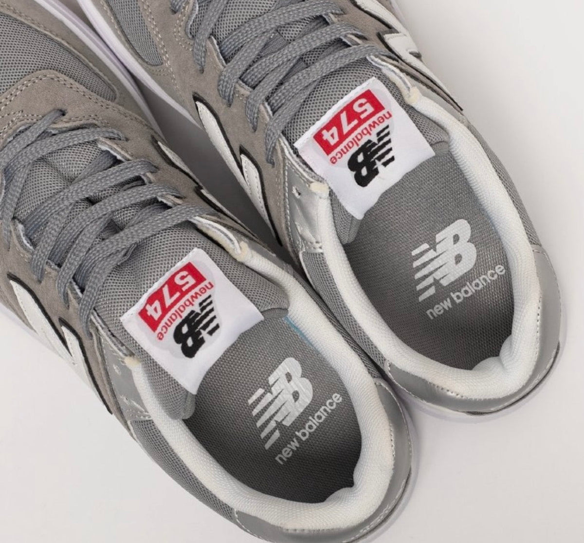 Cette chaussure est la New Balance Numeric 574 Vulc (référence couleur Grey/White), modèle classique iconique de la marque américaine New Balance