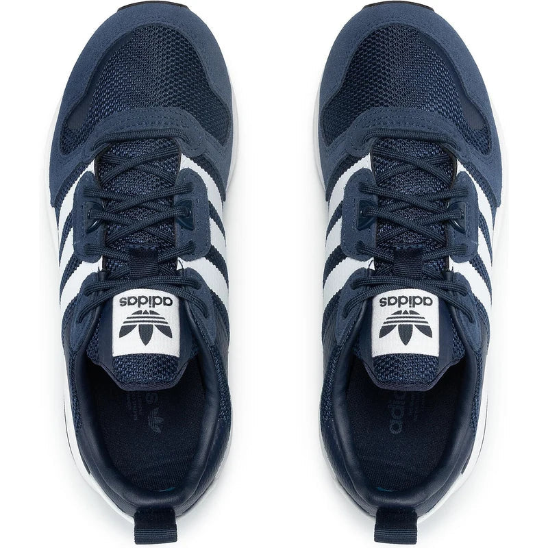 Le modèle présenté dans l'image est la adidas ZX 700 HD dans son coloris bleu marine classique avec les trois bandes blanches caractéristiques de la marque adidas.
