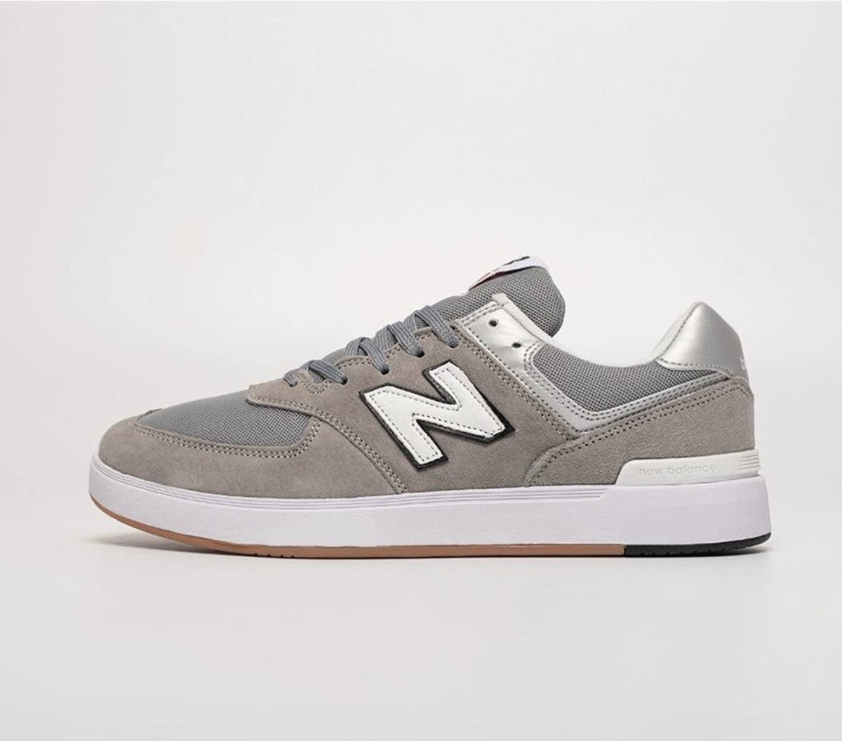 Cette chaussure est la New Balance Numeric 574 Vulc (référence couleur Grey/White), modèle classique iconique de la marque américaine New Balance